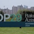 A large sign on a green lawn says COP20 Baku Azerbaijan with tall buildings in the background